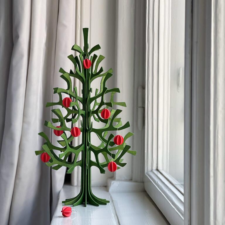 Lovi Spruce 30cm forest green with bright red Lovi Minibaubles on windowsill. Wooden Christmas tree.