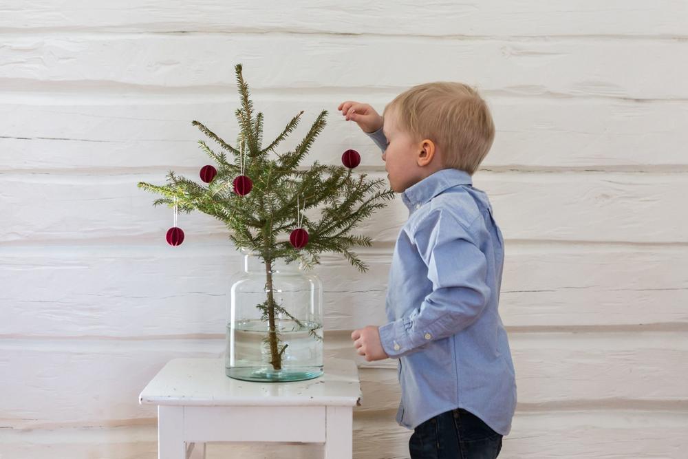 A little boy decorating a Christmas tree with small Lovi Baubles.
