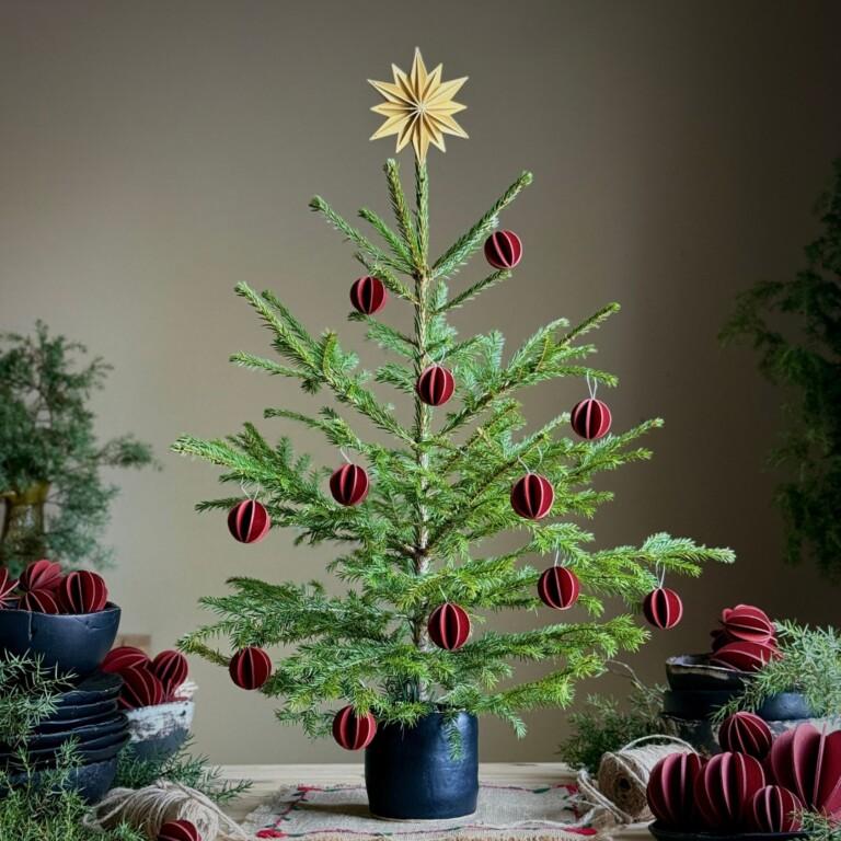 Tabletop Christmas tree decorated with Lovi Christmas Decoration Set 10cm and 3.3cm, honey yellow and rustic red, wooden tree top star and baubles.